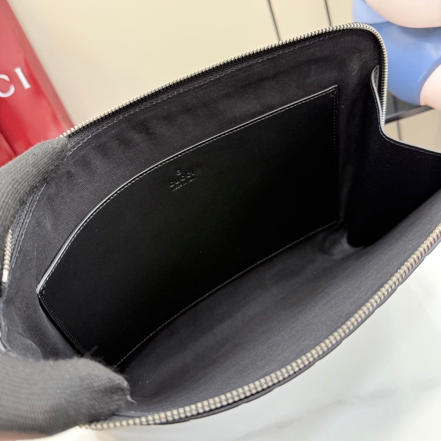 Gucci pouch bag interior view with black fabric lining and zippered opening.