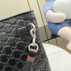 Gucci small bag detail: embossed monogram, metal ring clasp and web strap.