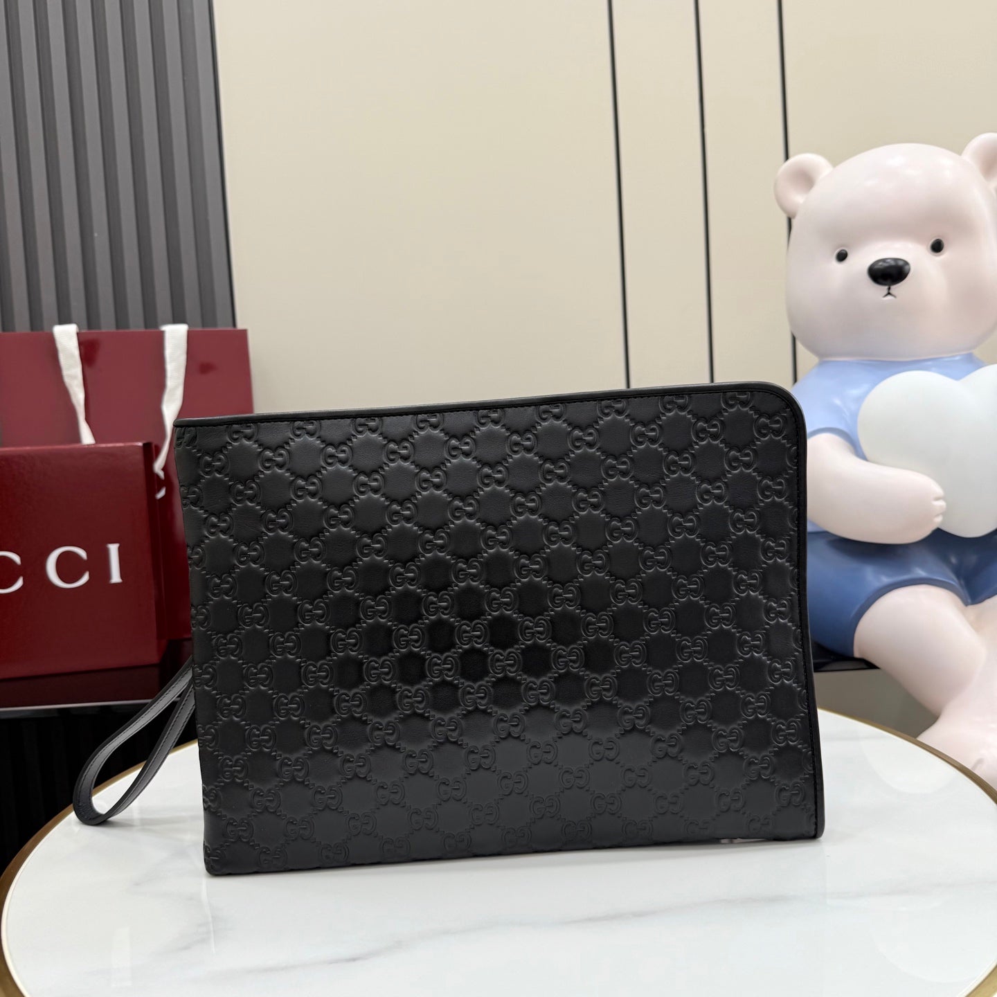 Gucci small bag, dark GG-pattern canvas with flap and wrist strap.