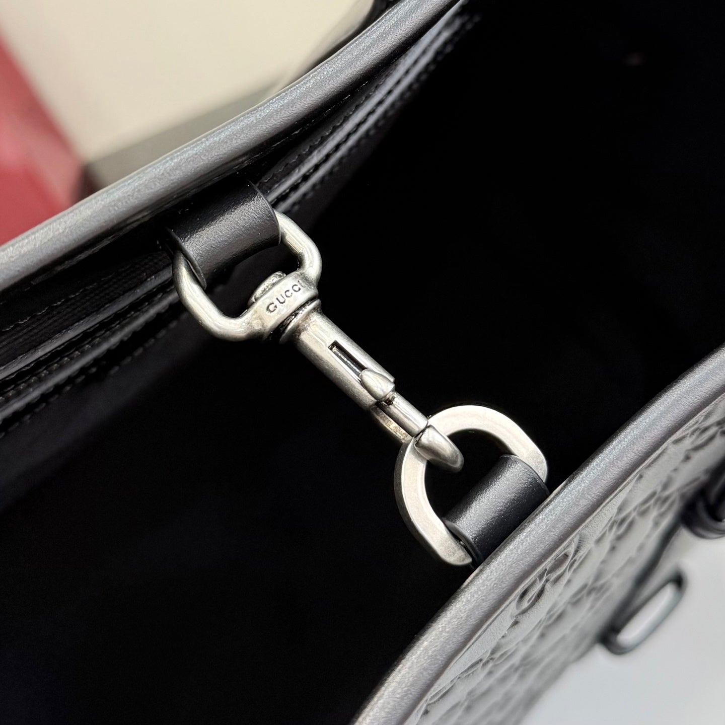 Tote bag hardware close-up: dark strap, silver clasp, and top edge trim