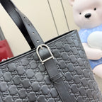 Close-up of dark gray monogram tote with adjustable shoulder strap and buckle