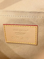Leather brand patch reading Louis Vuitton MURAKAMI on beige background with embossed icons