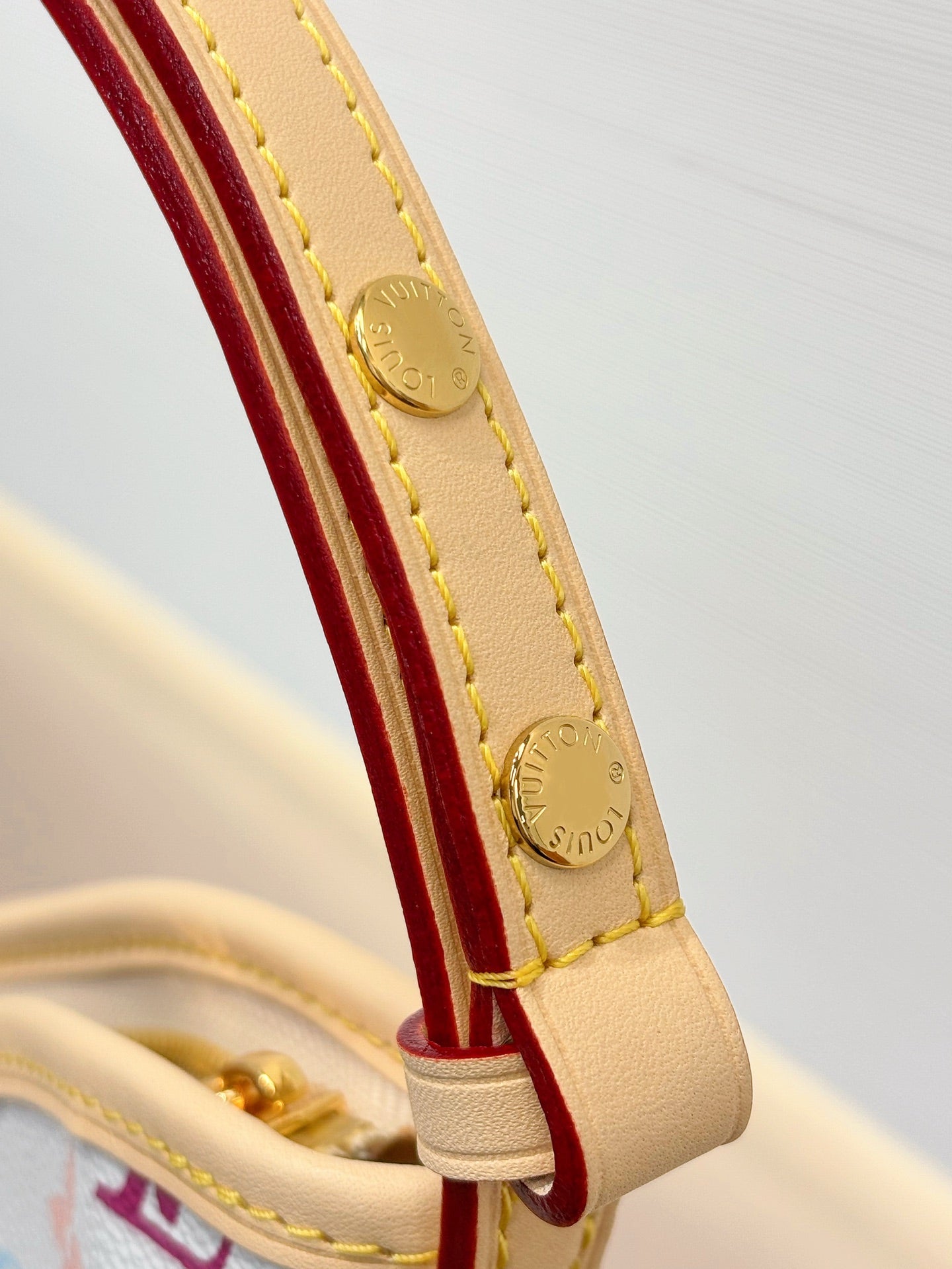 Beige strap loop with gold hardware on multicolor monogram hobo bag