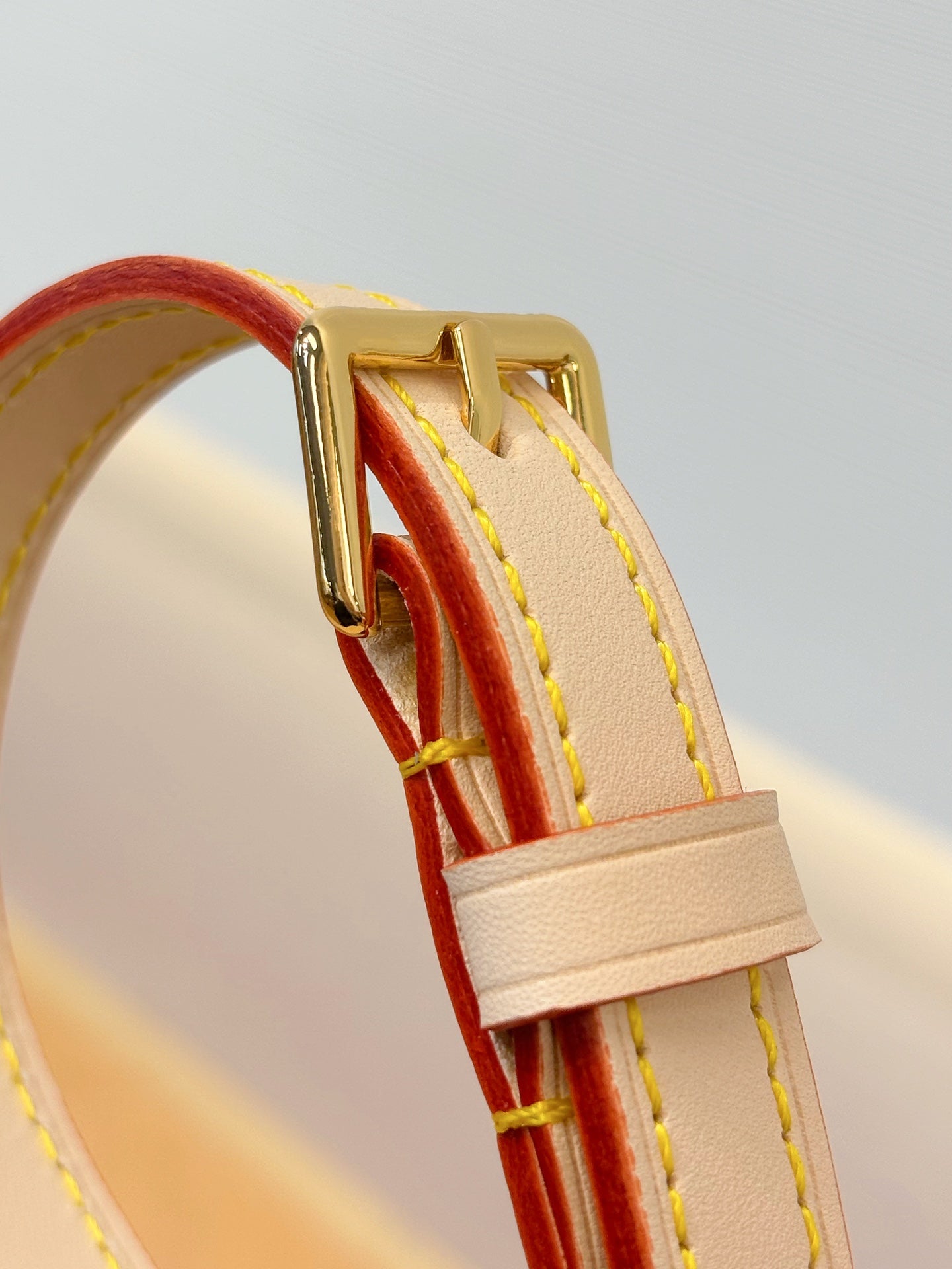 Bag strap corner with red and white leather trim and gold hardware