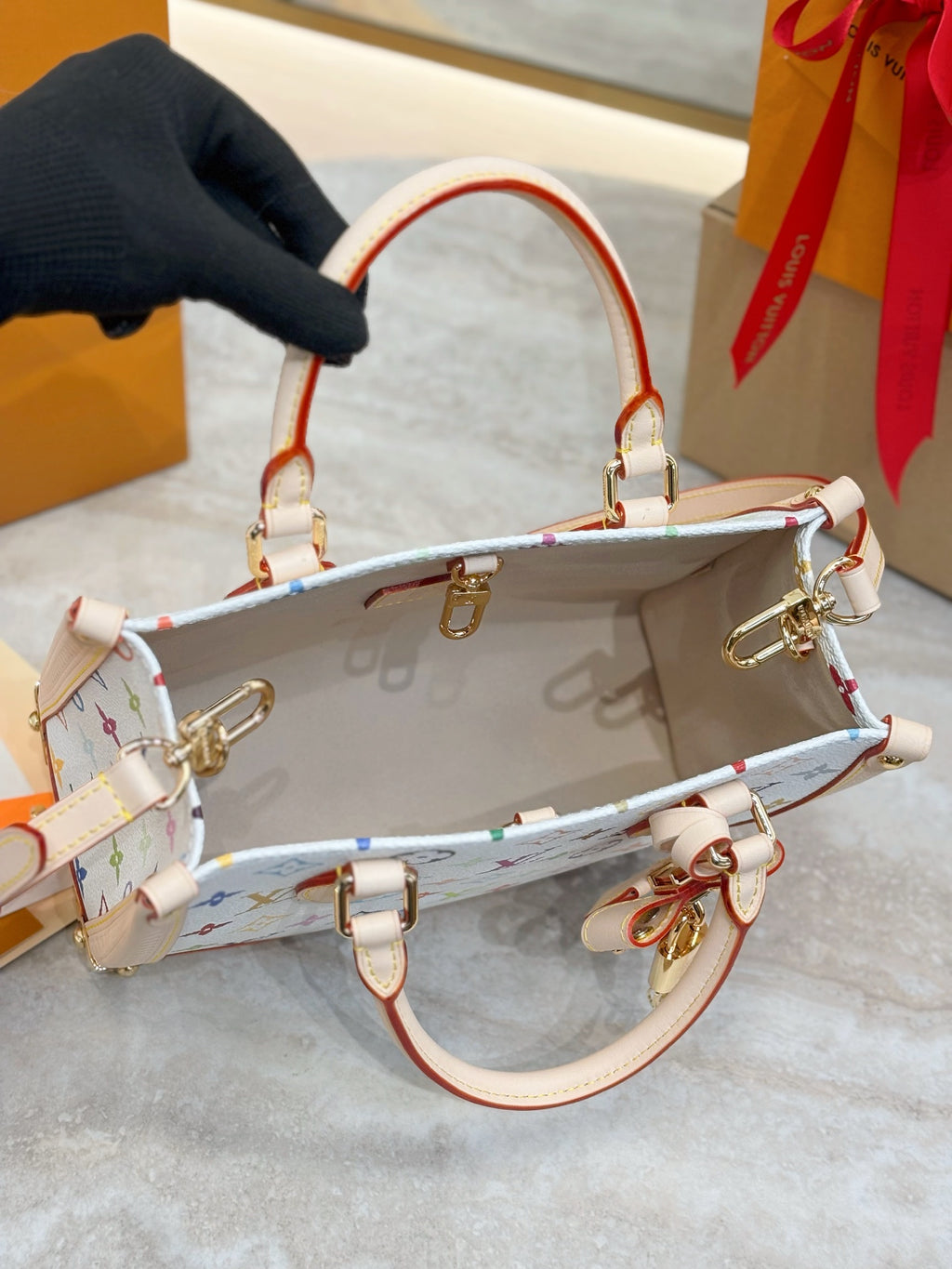 Multicolor monogram bag with red-and-white strap, open top, gold clasps