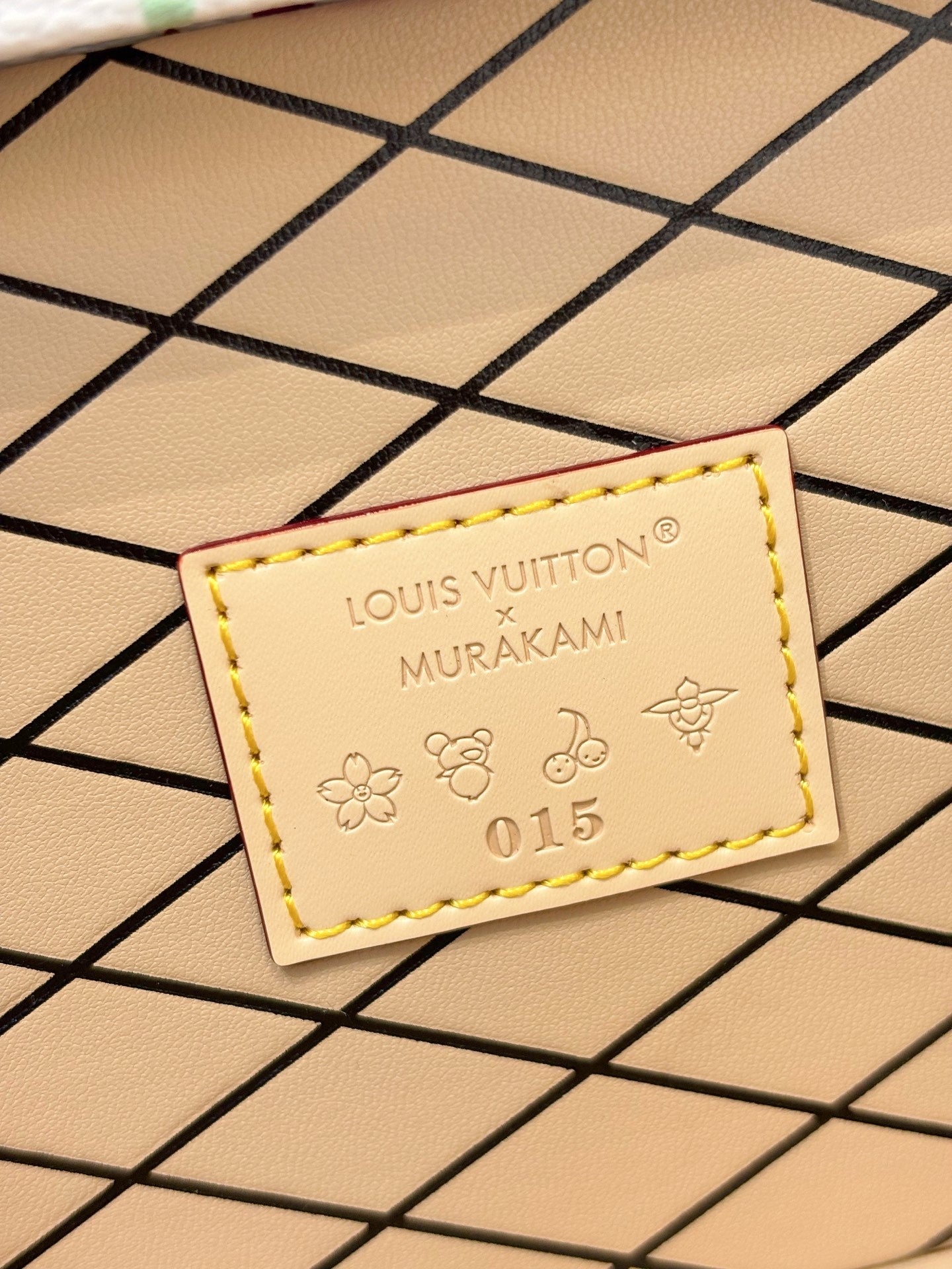 Louis Vuitton Murakami leather tag showing '015' and flower motifs on beige panel