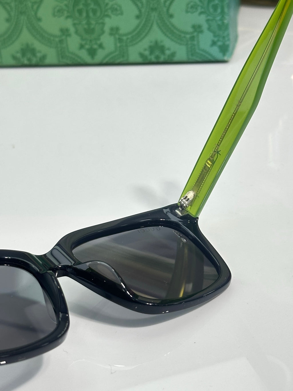 Gucci sunglasses arm detail with green temple and dark lens front