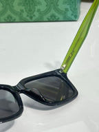 Gucci sunglasses arm detail with green temple and dark lens front