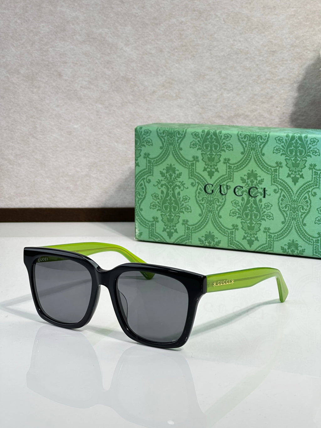 Gucci sunglasses with black frames, green temple tips, and dark lenses