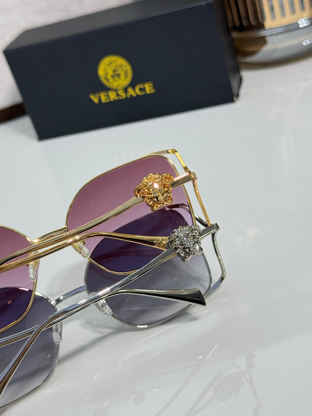 Versace sunglasses close-up, gold and silver frame with purple tinted lens