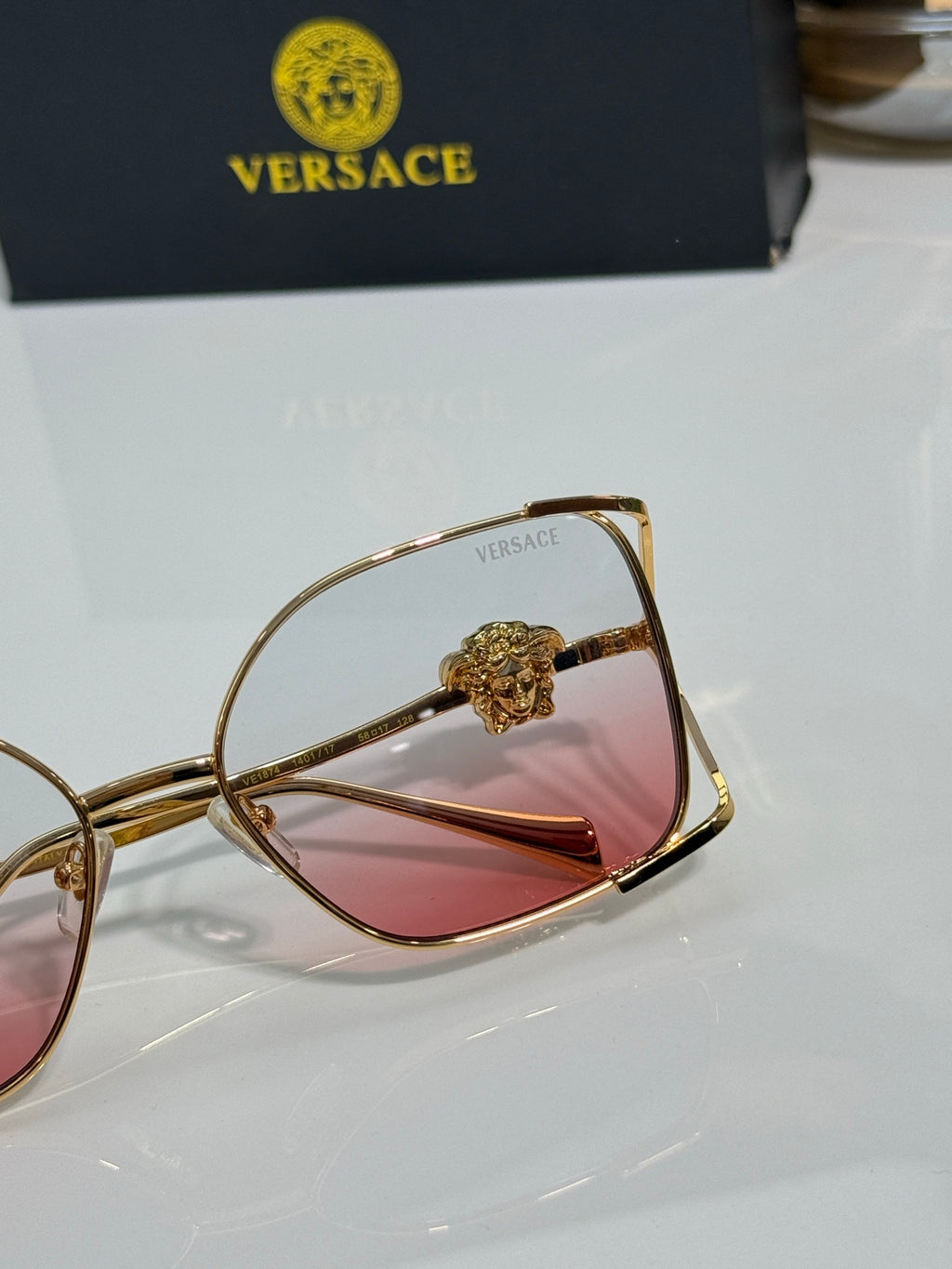 Versace sunglasses close-up, gold frame with rose tinted lens and crown detail