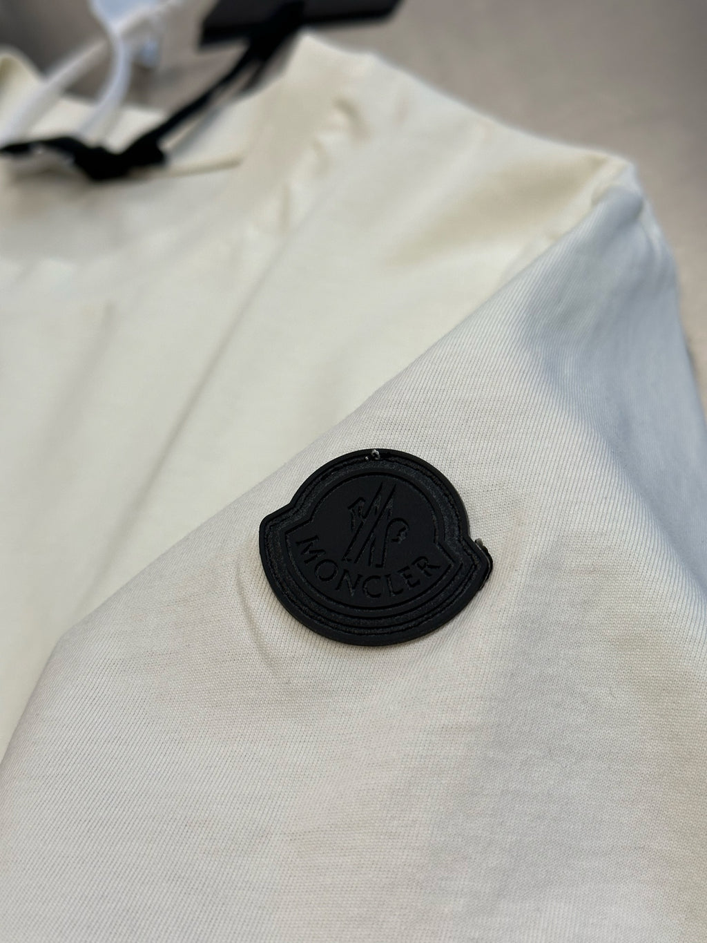 Cream T-shirt with small black embroidered patch logo
