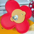 Close-up red leather flower charm with beige center patch and heart stud detail.