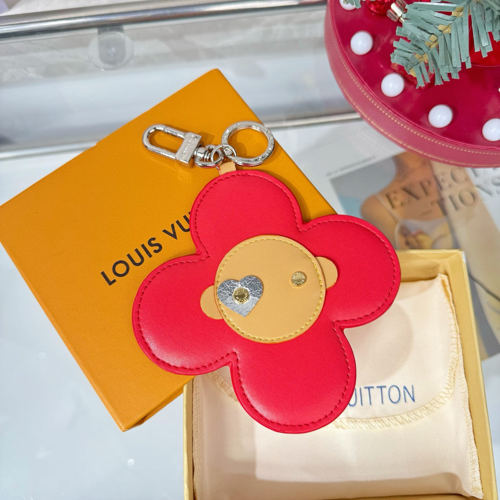 Red leather flower keychain with beige heart patch and silver clasp attachment.