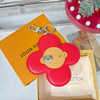 Red leather flower keychain with beige heart patch and silver clasp attachment.