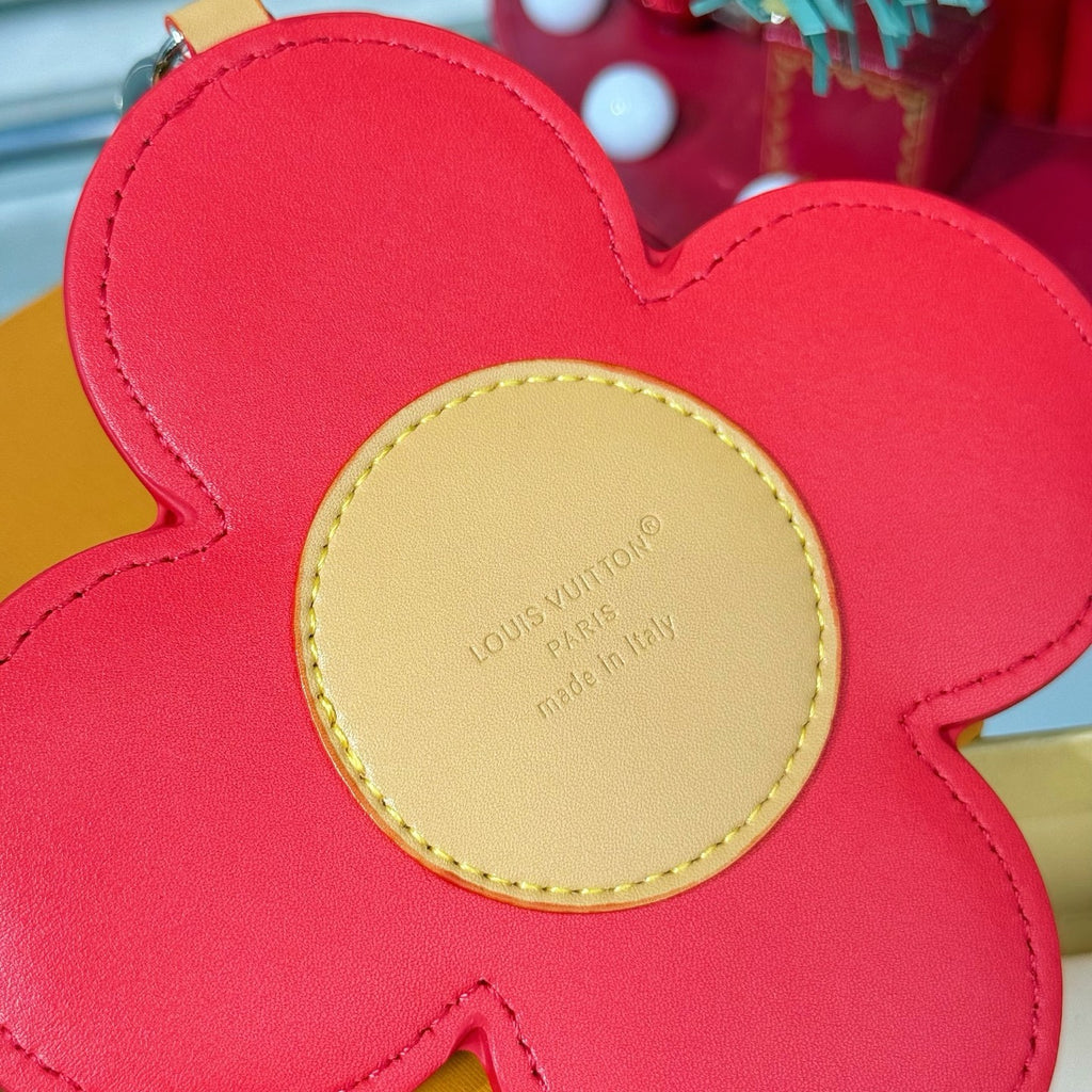 Red leather flower charm with beige center label, stitched edges, and rounded petals.