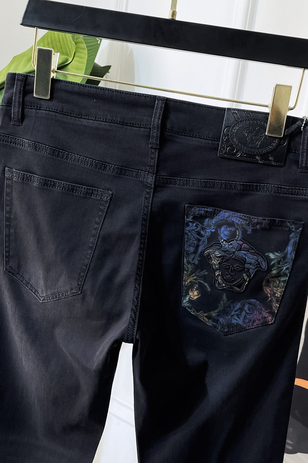 Dark denim jeans with embossed logo patch and embroidered pocket graphic