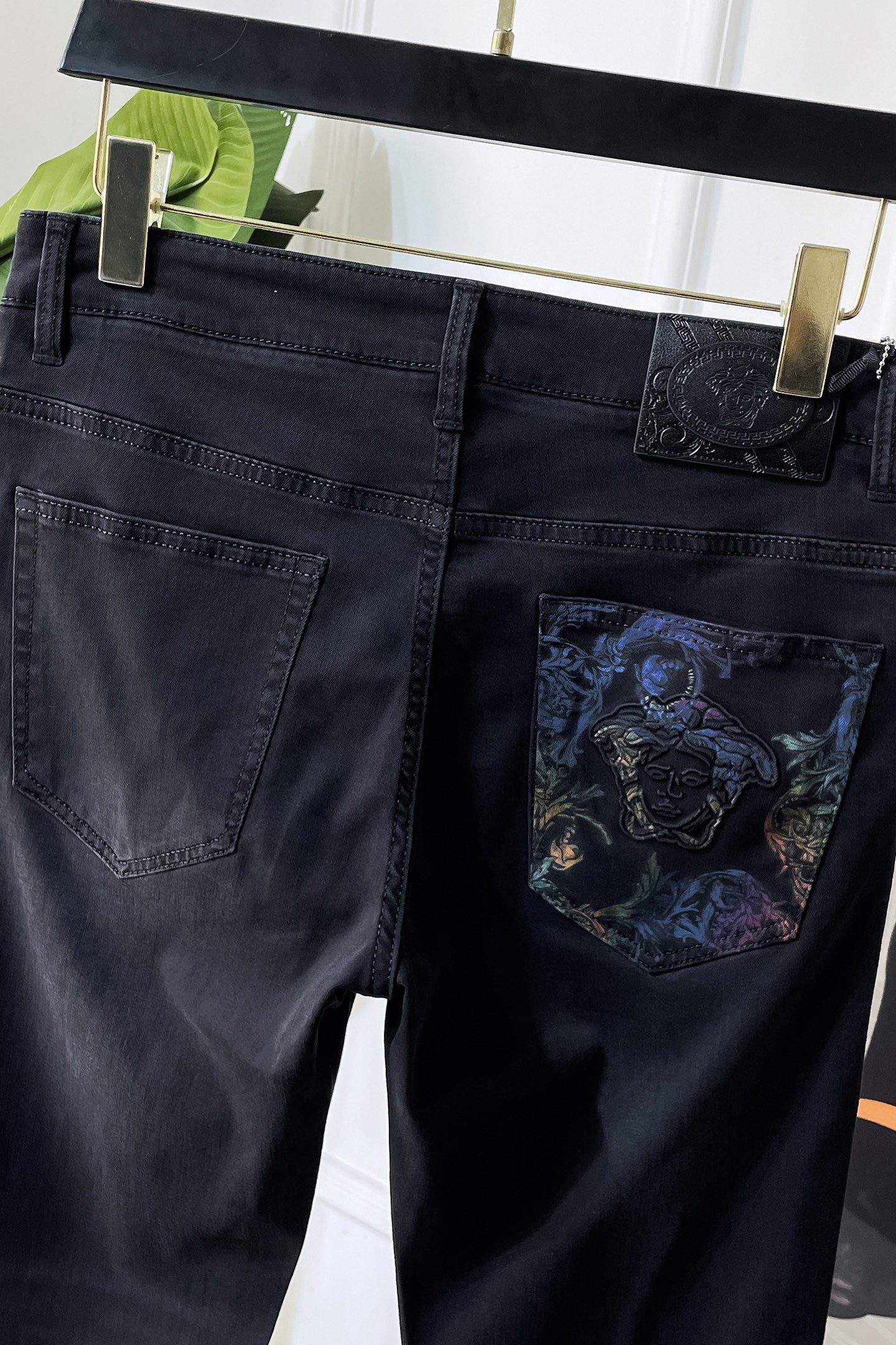 Dark denim jeans with embossed logo patch and embroidered pocket graphic