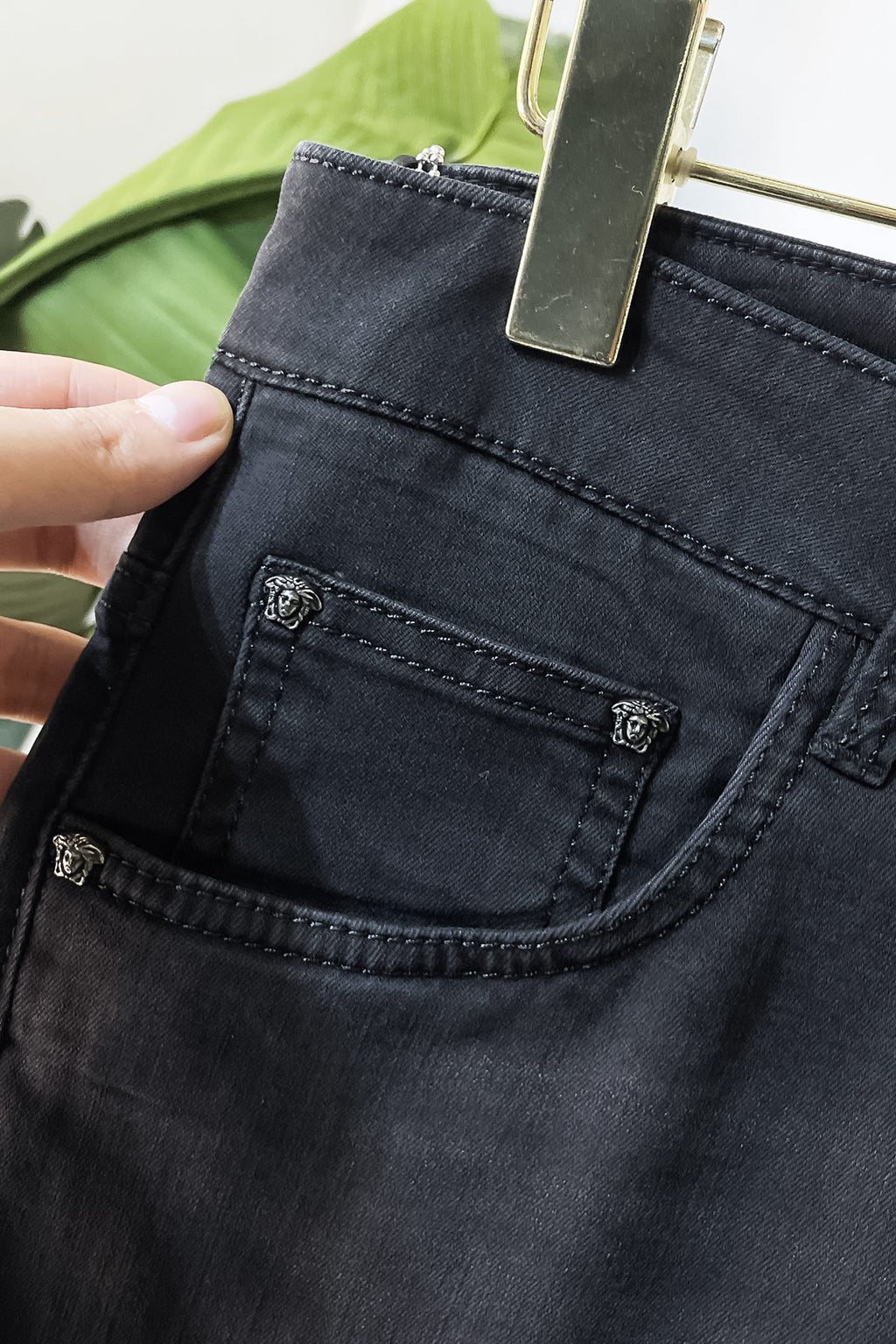 Dark denim jeans front pocket with stitched panel and metal logo stud