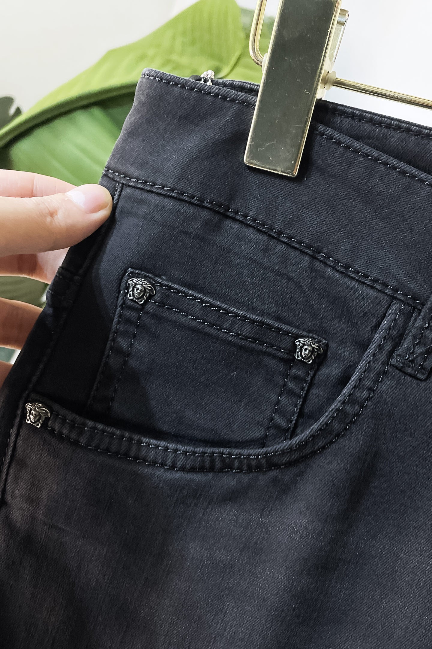 Dark denim jeans front pocket with stitched panel and metal logo stud