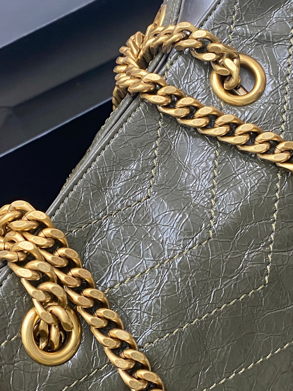 Gold chain handle and ring hardware on dark green pebbled leather tote