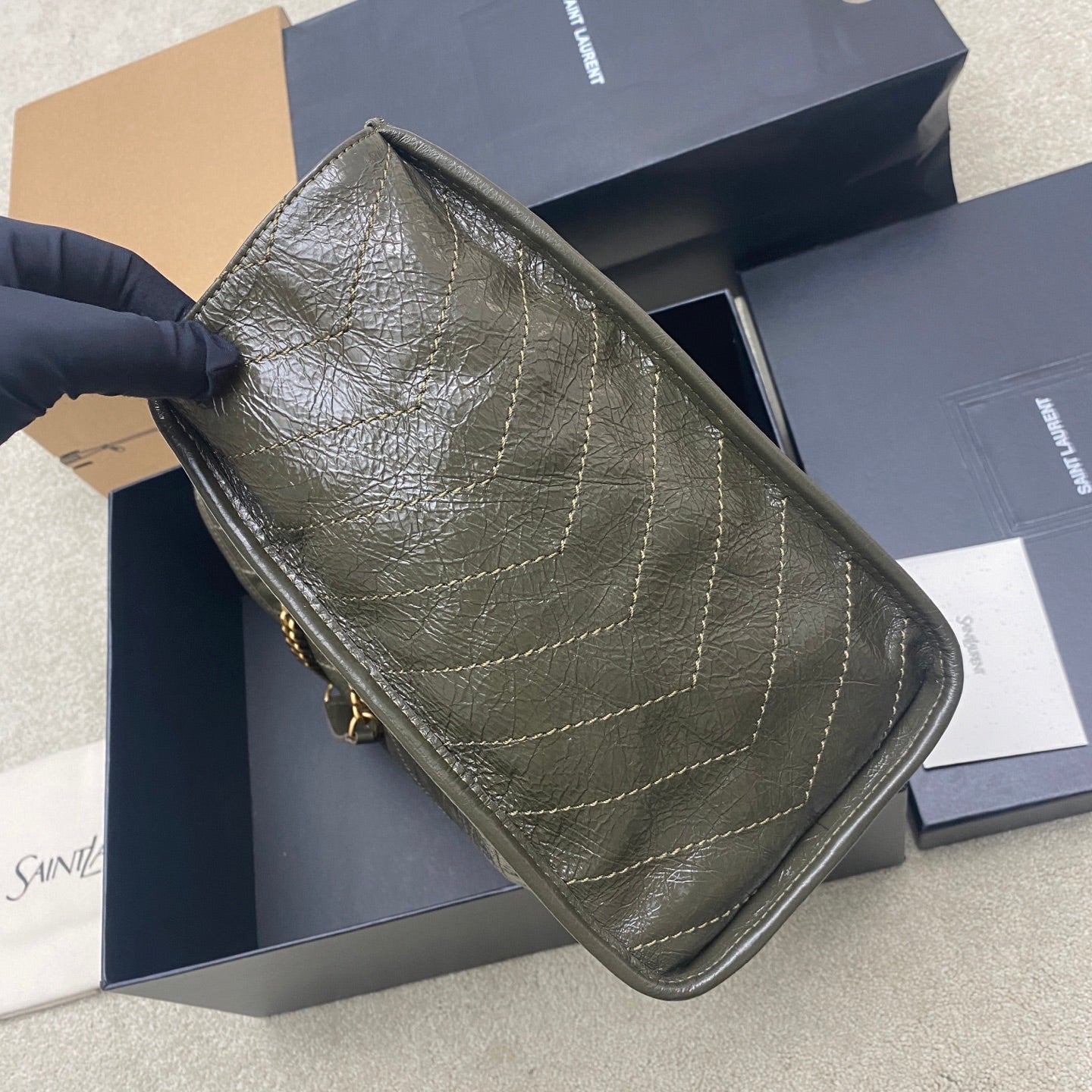 Tote bag in dark green pebbled leather with gold chain handle and stitched seams