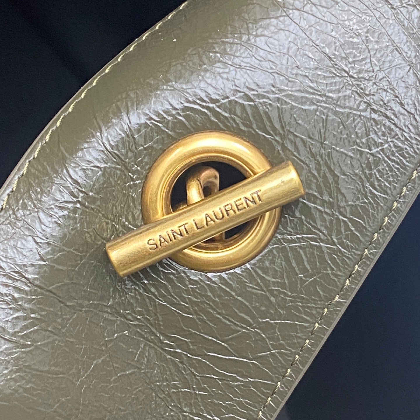 Gold Saint Laurent logo push-lock on dark green pebbled leather bag