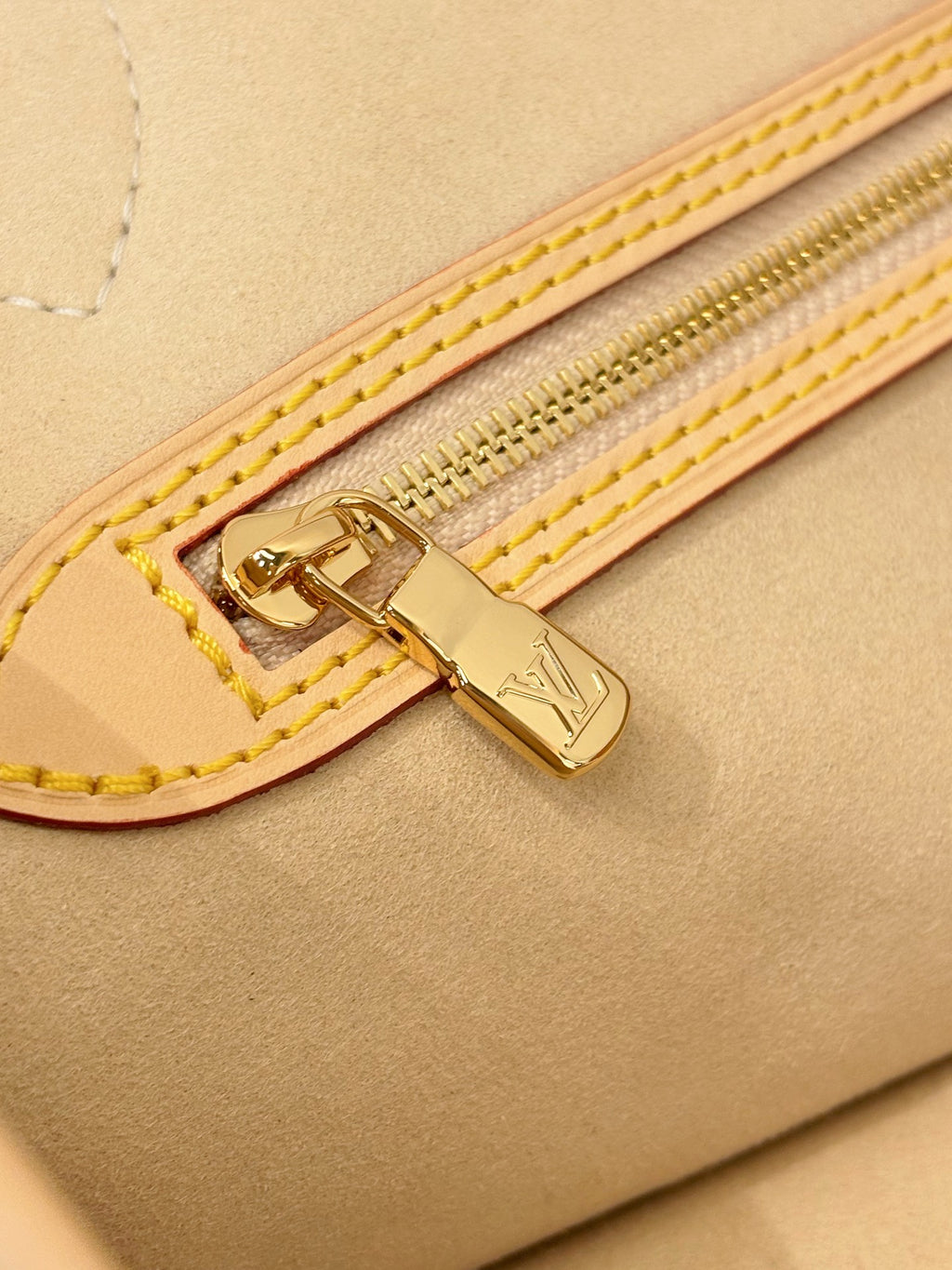 Louis Vuitton zipper trim on tan bag with gold hardware and double yellow stitching