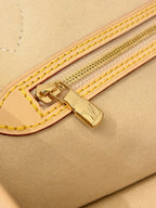 Louis Vuitton zipper trim on tan bag with gold hardware and double yellow stitching