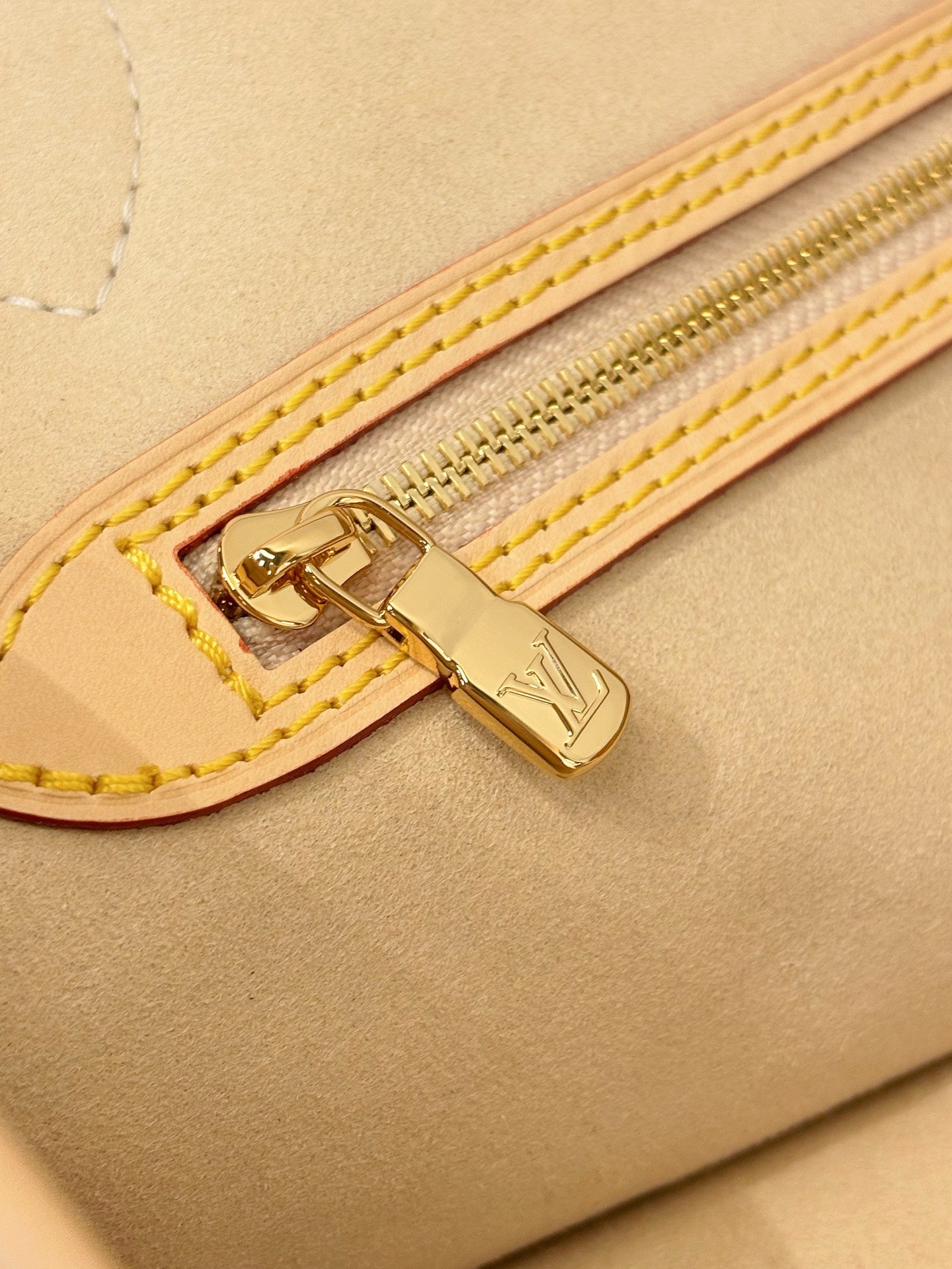 Louis Vuitton zipper trim on tan bag with gold hardware and double yellow stitching