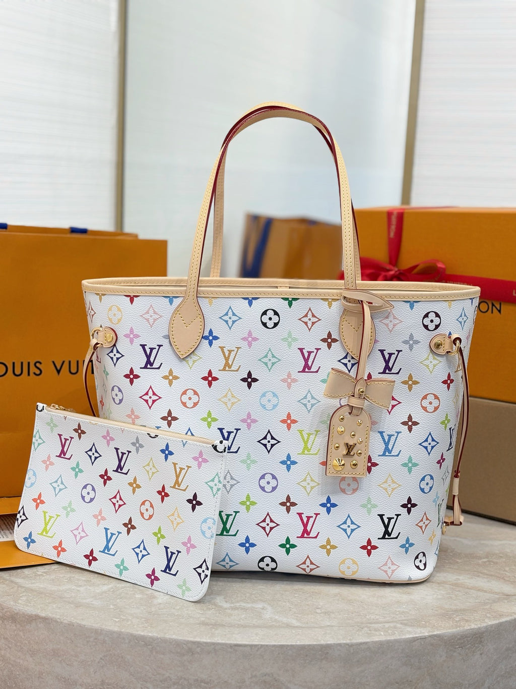 Louis Vuitton tote bag with multicolor monogram pattern, tan handles, and zipper pouch