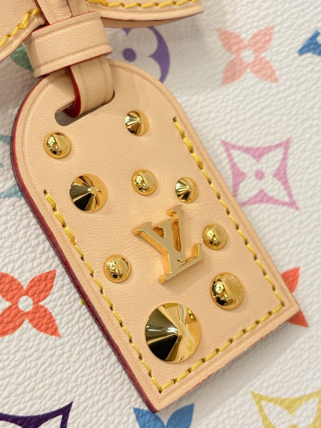 Louis Vuitton leather charm with gold studs and logo on multicolor monogram strap