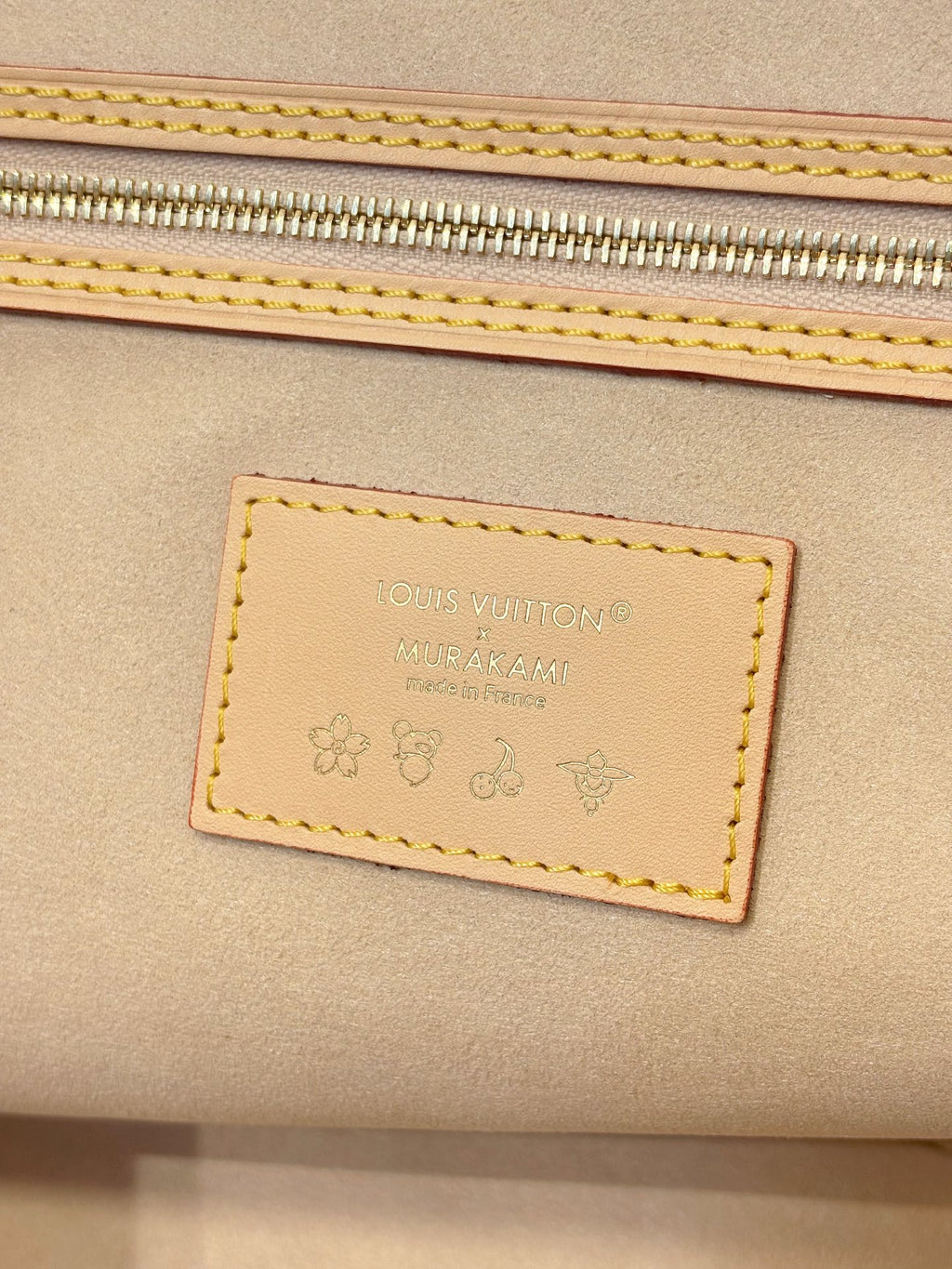 Louis Vuitton leather brand patch on tan bag panel with stitched border