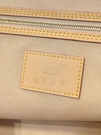 Louis Vuitton leather brand patch on tan bag panel with stitched border