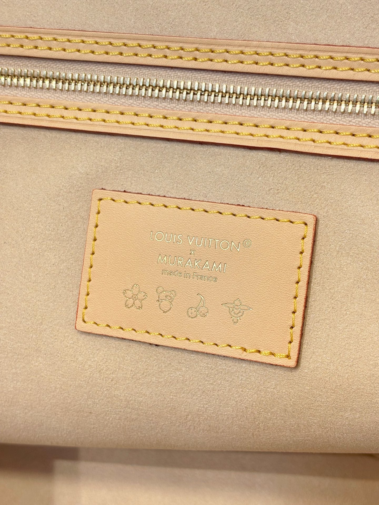 Louis Vuitton leather brand patch on tan bag panel with stitched border