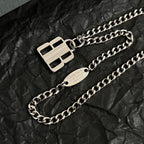 Silver-tone chain necklace with square logo charm and oval name tag