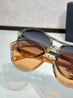 Chanel sunglasses close-up with gold frames and amber tinted lenses.