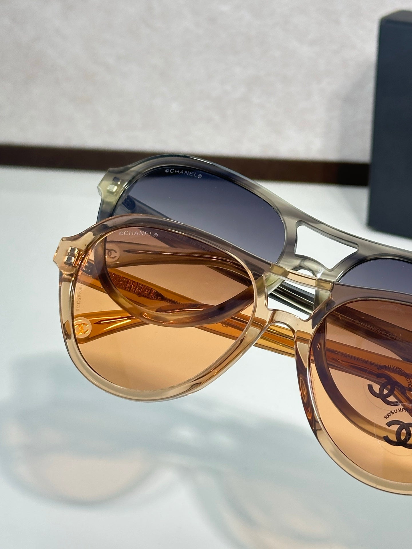 Chanel sunglasses close-up with gold frames and amber tinted lenses.
