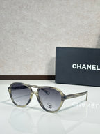 Chanel sunglasses with translucent olive-tinted frames and clear gray lenses.