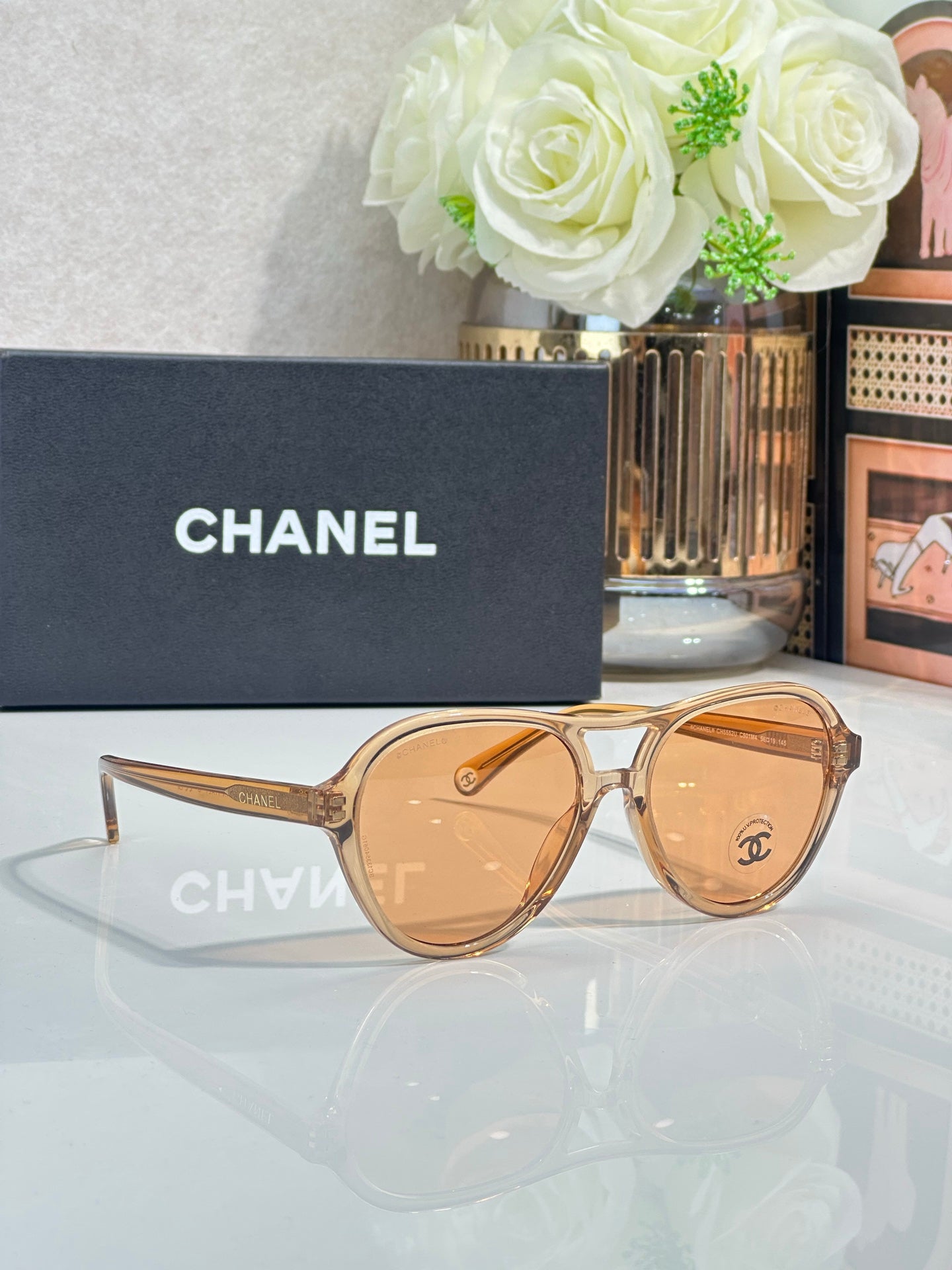 Chanel sunglasses with gold-tinted frames and warm amber lenses.