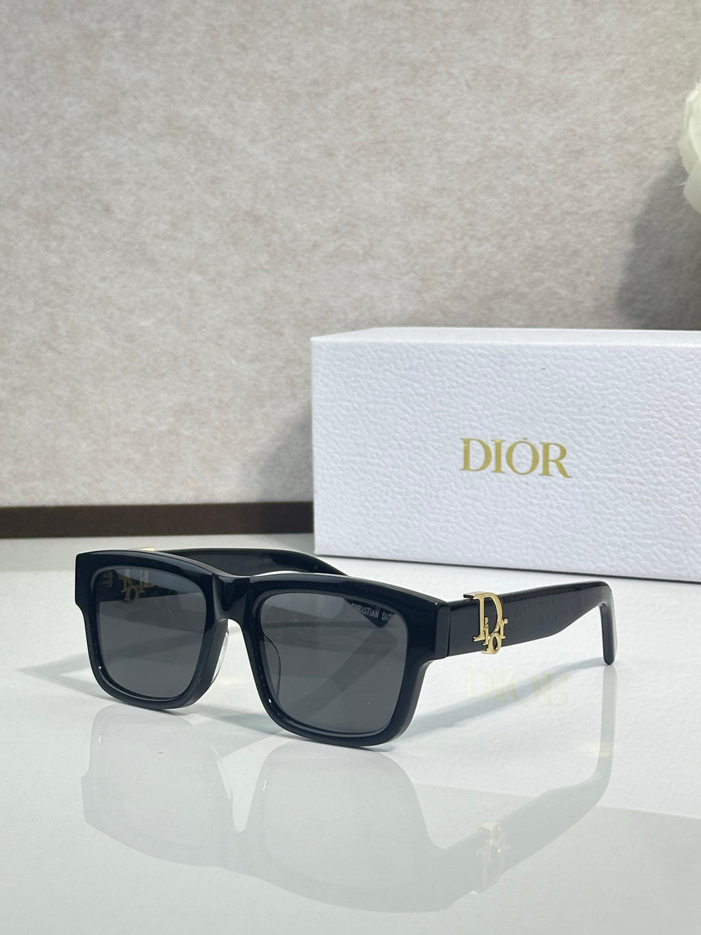 Black square sunglasses with dark lenses and gold logo bar on the bridge.