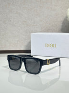 Black square sunglasses with dark lenses and gold logo bar on the bridge.