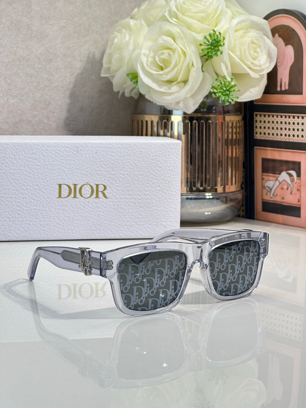 Silver square sunglasses with dark monogram lenses and gold logo bar detail.