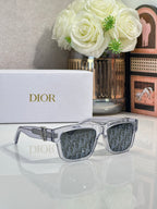 Silver square sunglasses with dark monogram lenses and gold logo bar detail.