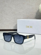 Black square sunglasses with dark monogram lenses and gold logo bar detail.