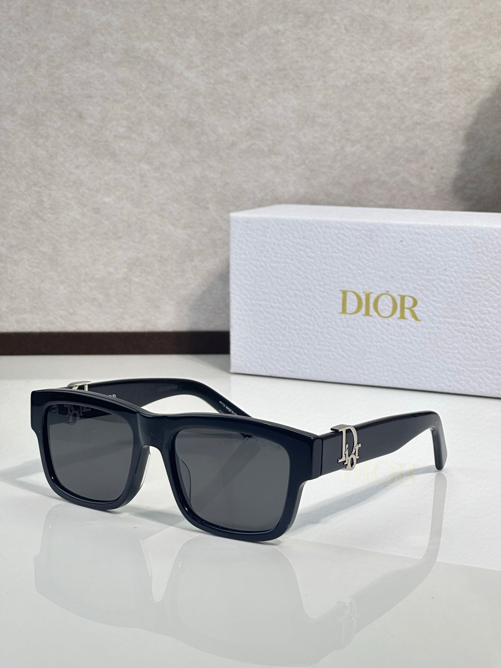 Black square sunglasses with dark lenses and gold logo detail on the temple.