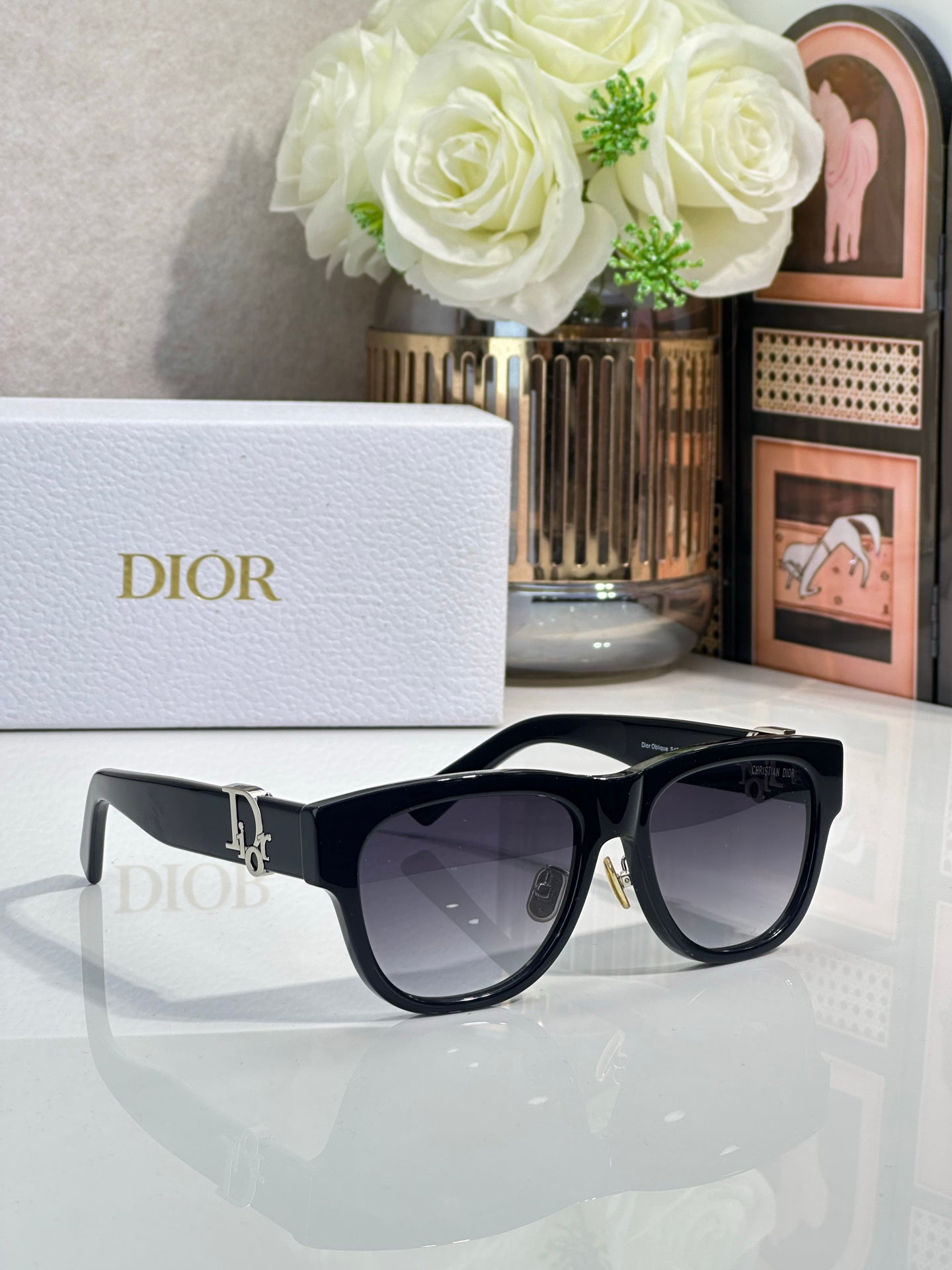 Dior sunglasses with black frames and dark lenses, gold logo detail on the side