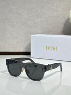Dior sunglasses with black frames and dark lenses, featuring a gold side logo detail