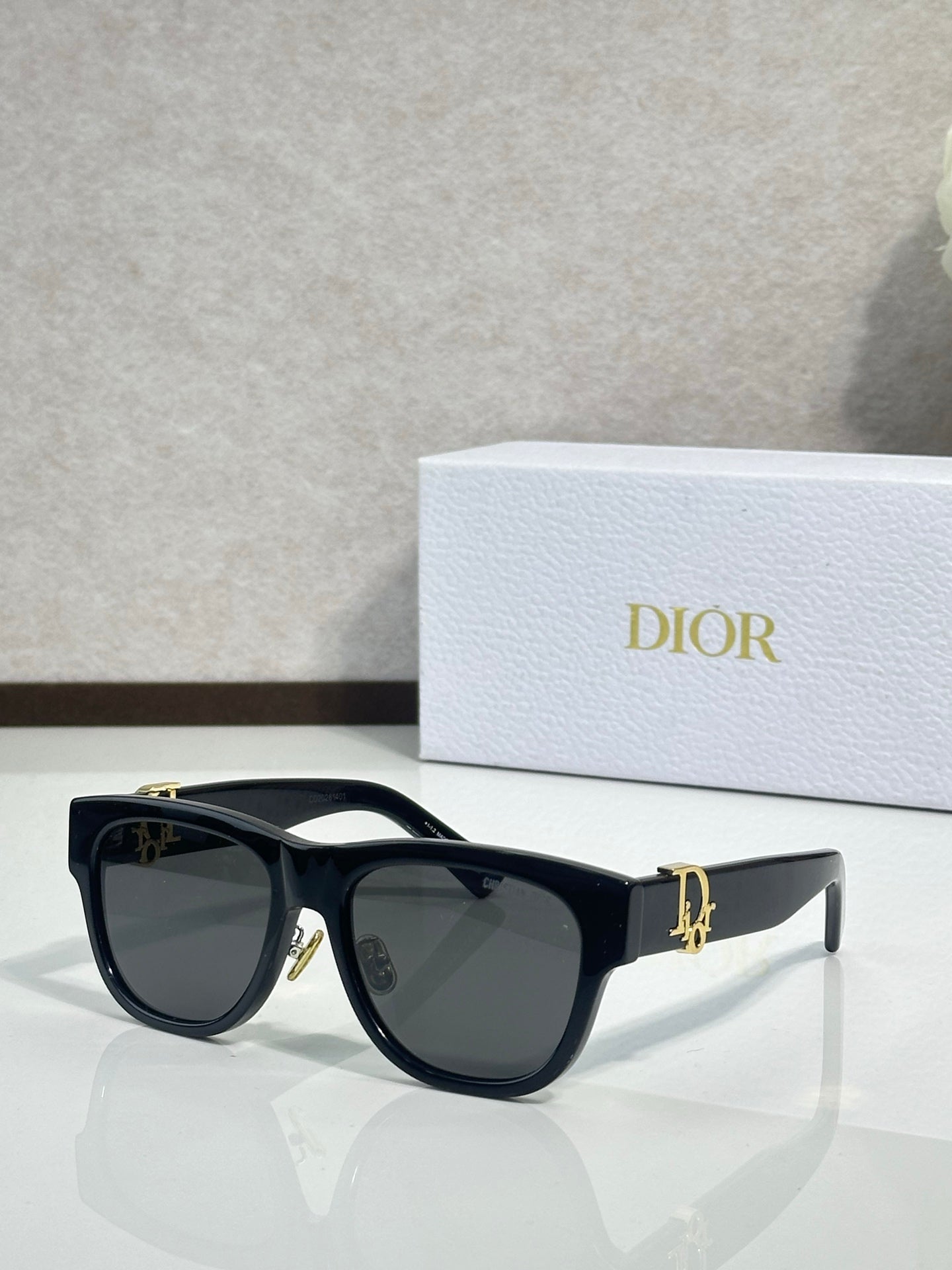 Dior sunglasses with black frames and dark lenses, gold logo detail on the temple