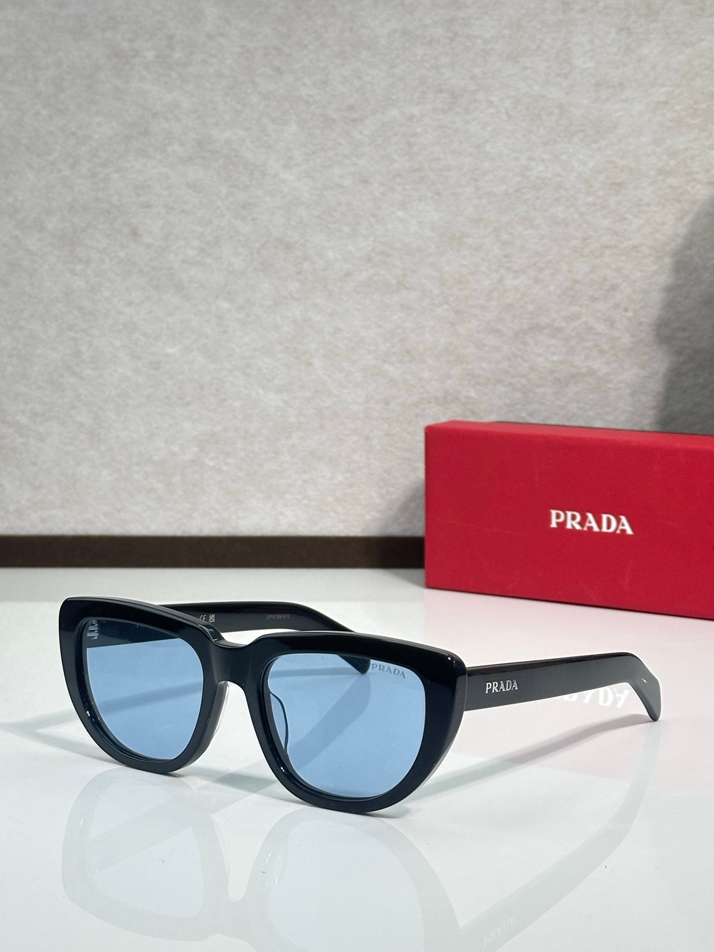 Prada sunglasses with dark frames and blue-tinted lenses, side view